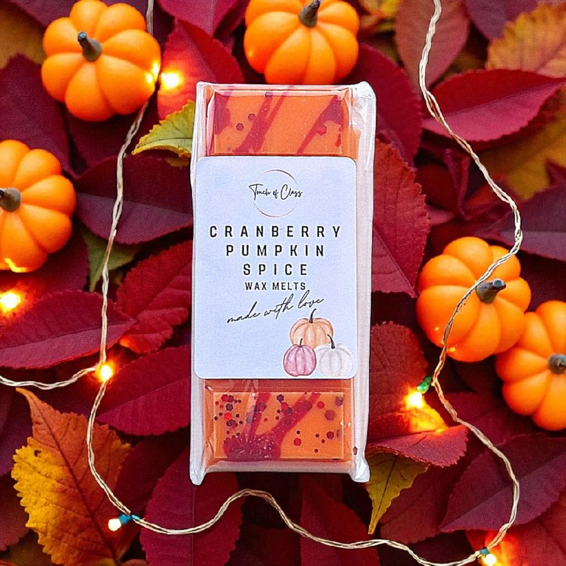 Cranberry Pumpkin Spice wax melts surrounded by pumpkins and leaves with string lights.