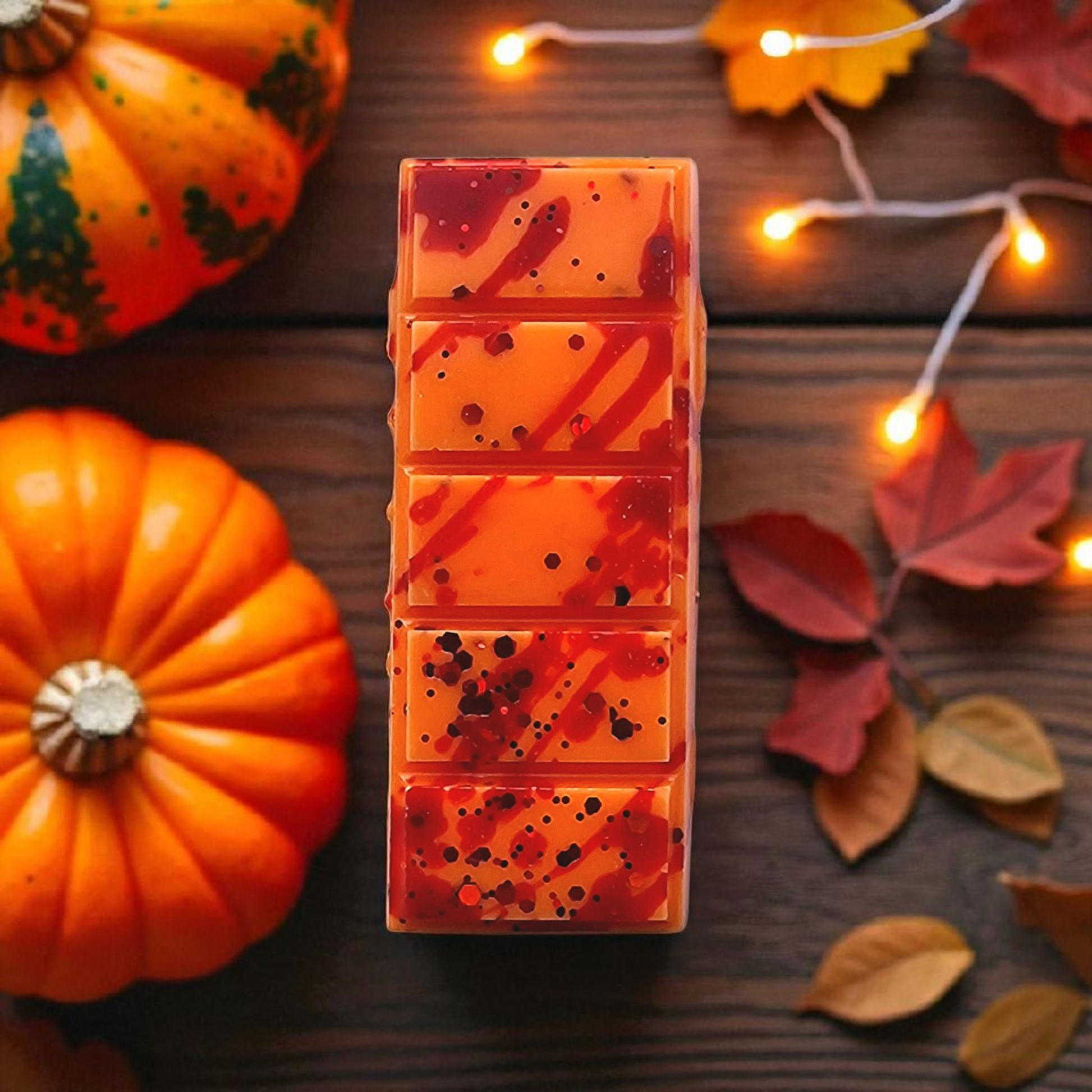 Cranberry pumpkin spice wax melt on a wooden surface with pumpkins and leaves.